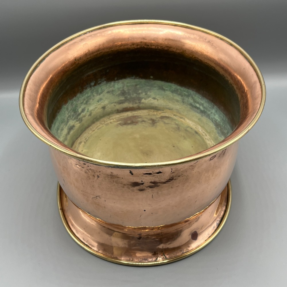 A large polished oval copper jardiniere with a flared rim edged in brass and a fitted flared brass base. View VII