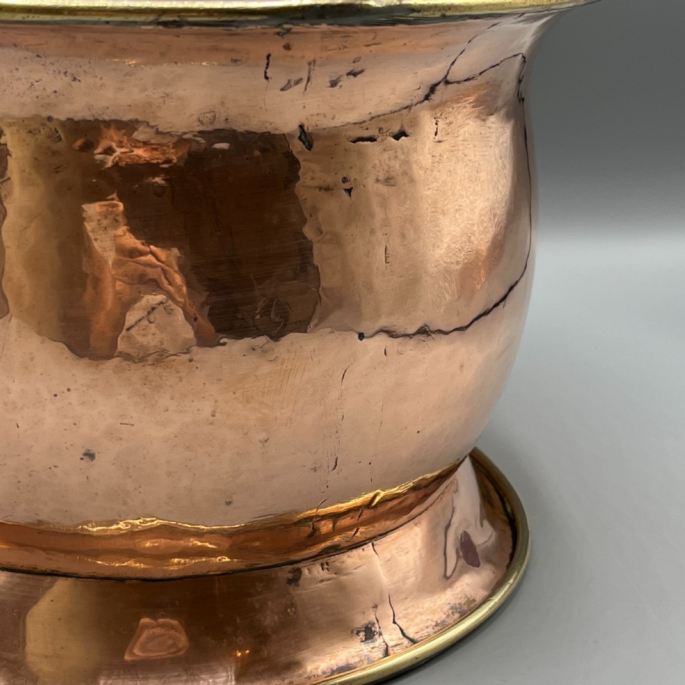 A large polished oval copper jardiniere with a flared rim edged in brass and a fitted flared brass base. View VIII