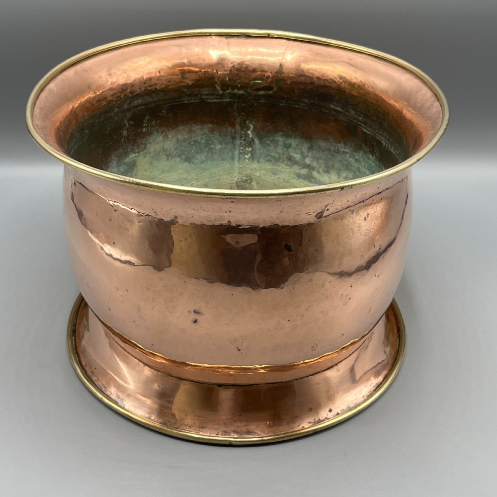 A large polished oval copper jardiniere with a flared rim edged in brass and a fitted flared brass base. View XIII