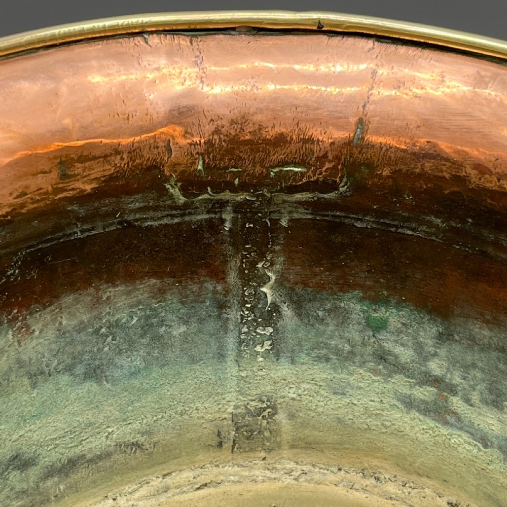 A large polished oval copper jardiniere with a flared rim edged in brass and a fitted flared brass base. View XVII