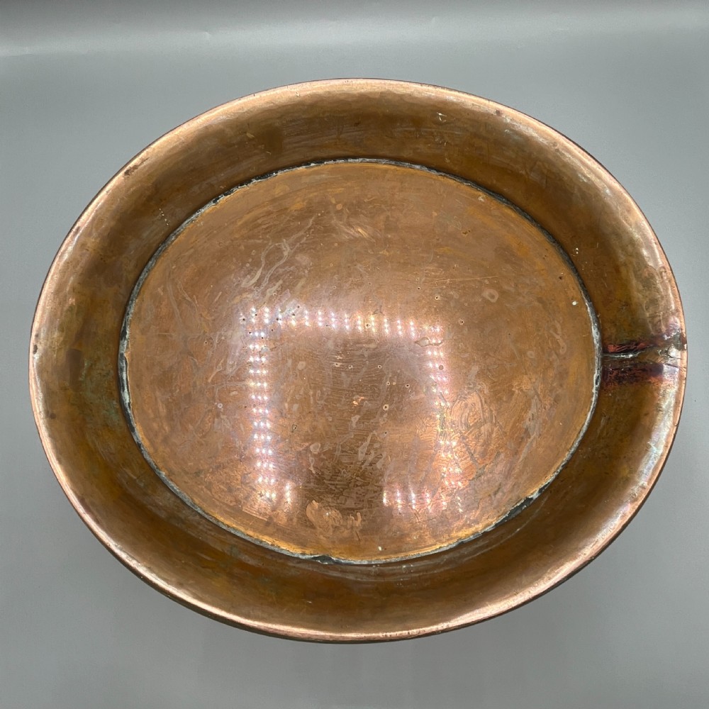 A large polished oval copper jardiniere with a flared rim edged in brass and a fitted flared brass base. View XIX