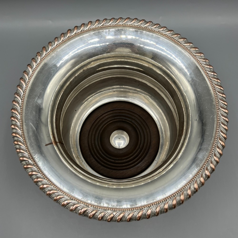 A circular silver-plated wine bottle coaster featuring a rope-twist detailed rim and a flared, polished body. View IV