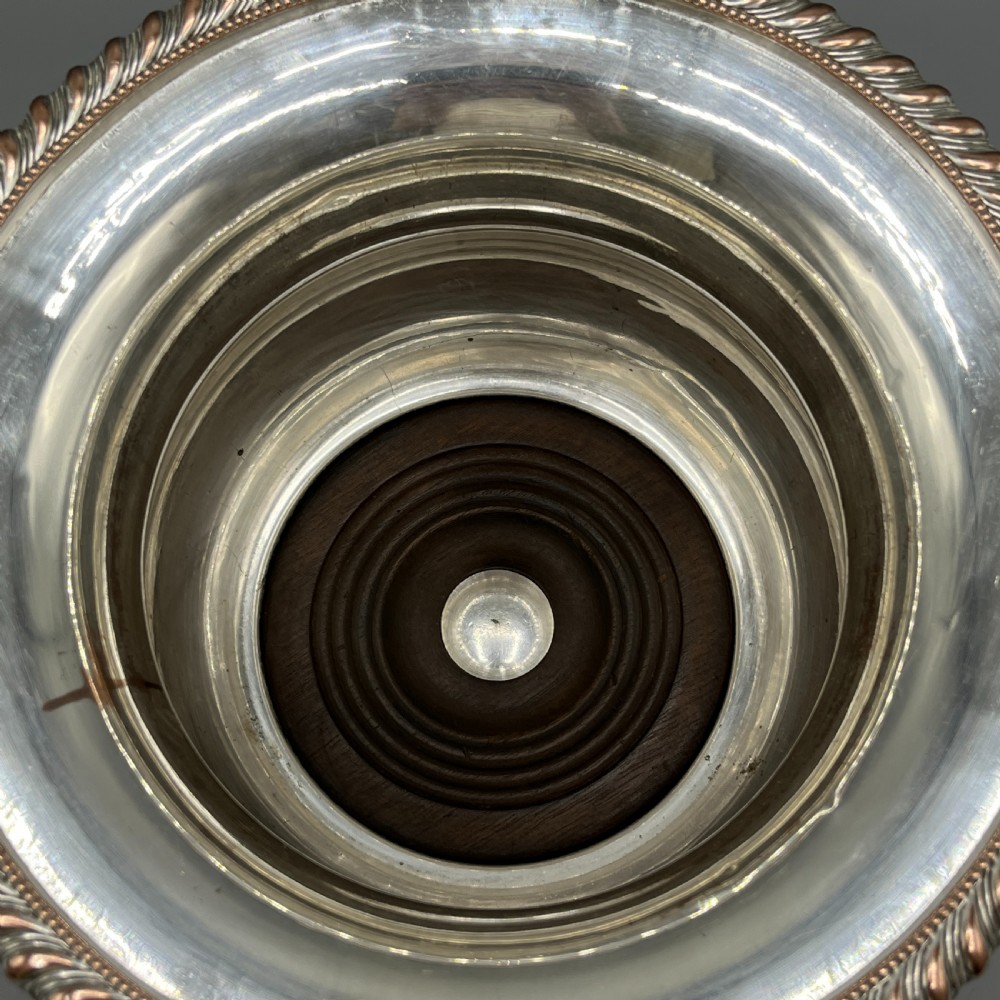 A circular silver-plated wine bottle coaster featuring a rope-twist detailed rim and a flared, polished body. View V