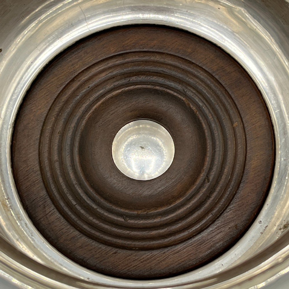 A circular silver-plated wine bottle coaster featuring a rope-twist detailed rim and a flared, polished body. View VI