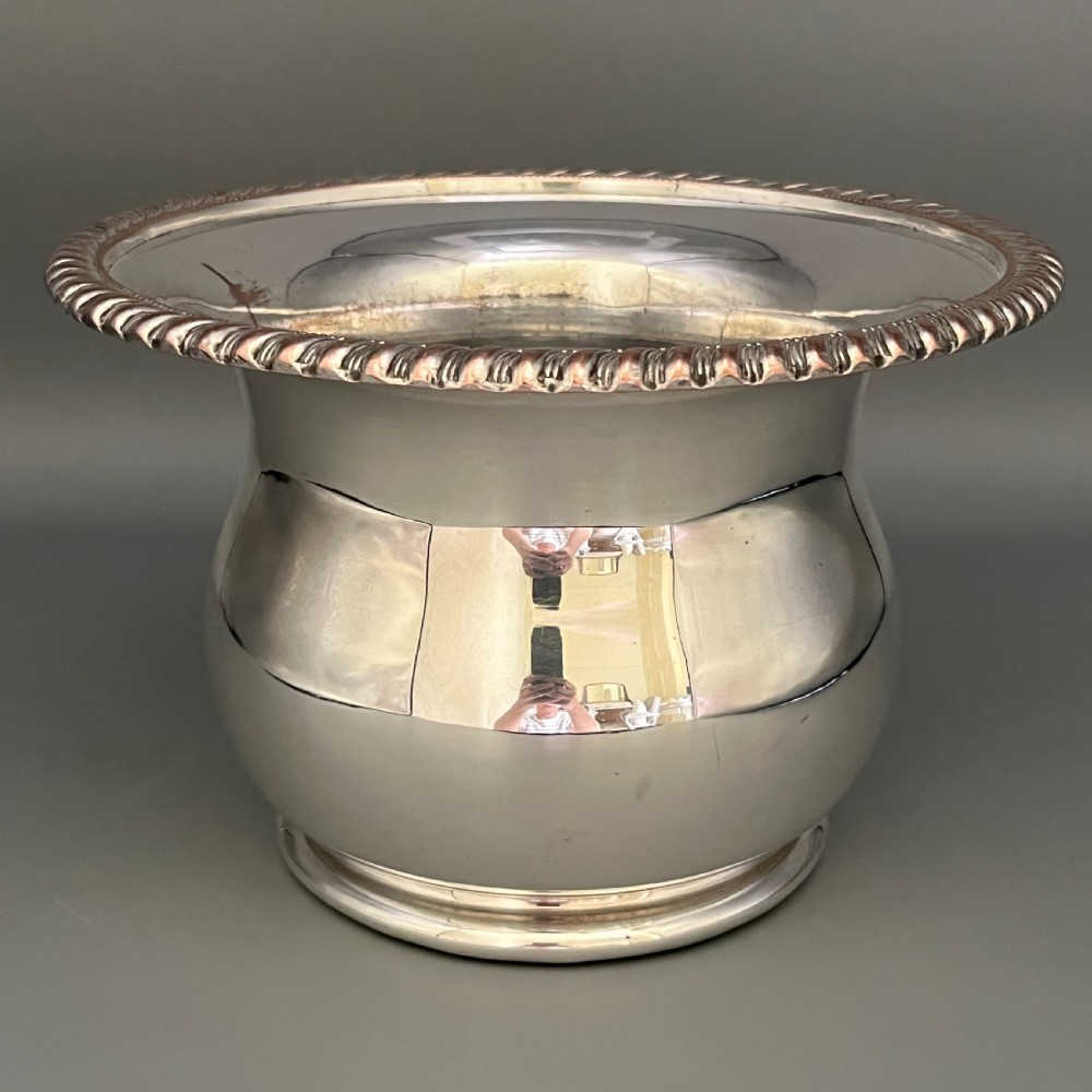 A circular silver-plated wine bottle coaster featuring a rope-twist detailed rim and a flared, polished body. View XIV