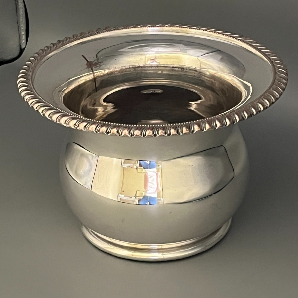 A circular silver-plated wine bottle coaster featuring a rope-twist detailed rim and a flared, polished body. View XVI