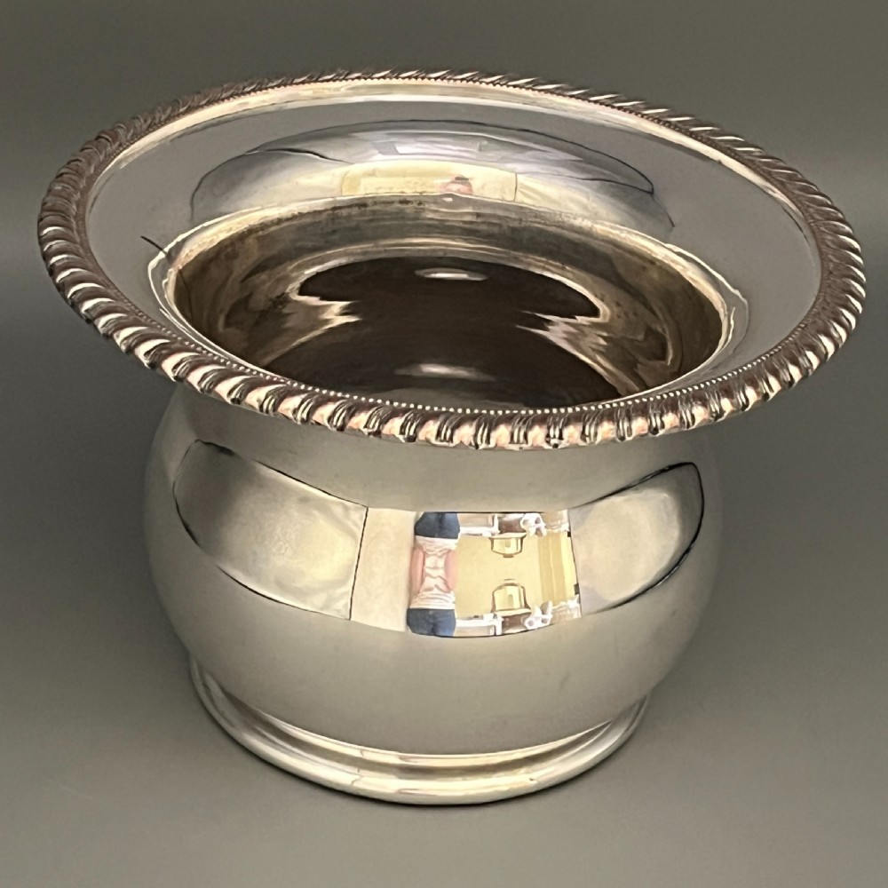 A circular silver-plated wine bottle coaster featuring a rope-twist detailed rim and a flared, polished body. View XVII