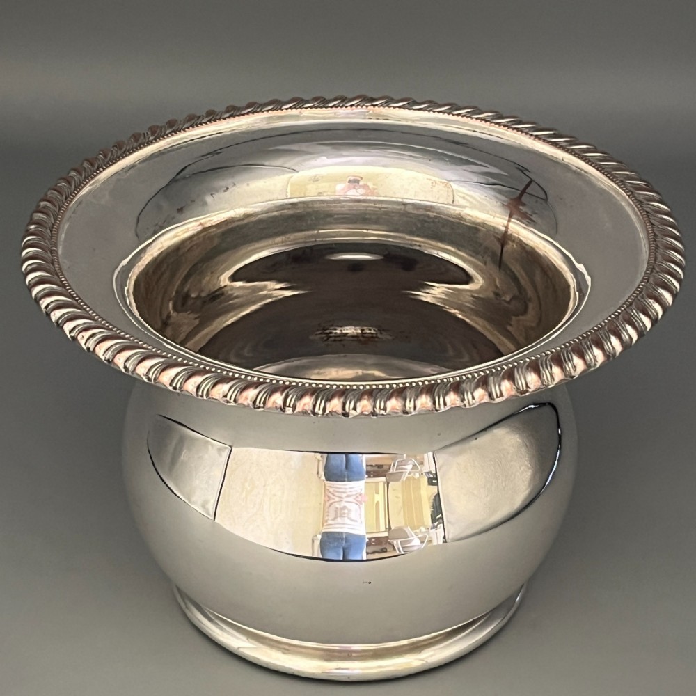 A circular silver-plated wine bottle coaster featuring a rope-twist detailed rim and a flared, polished body. View XVIII