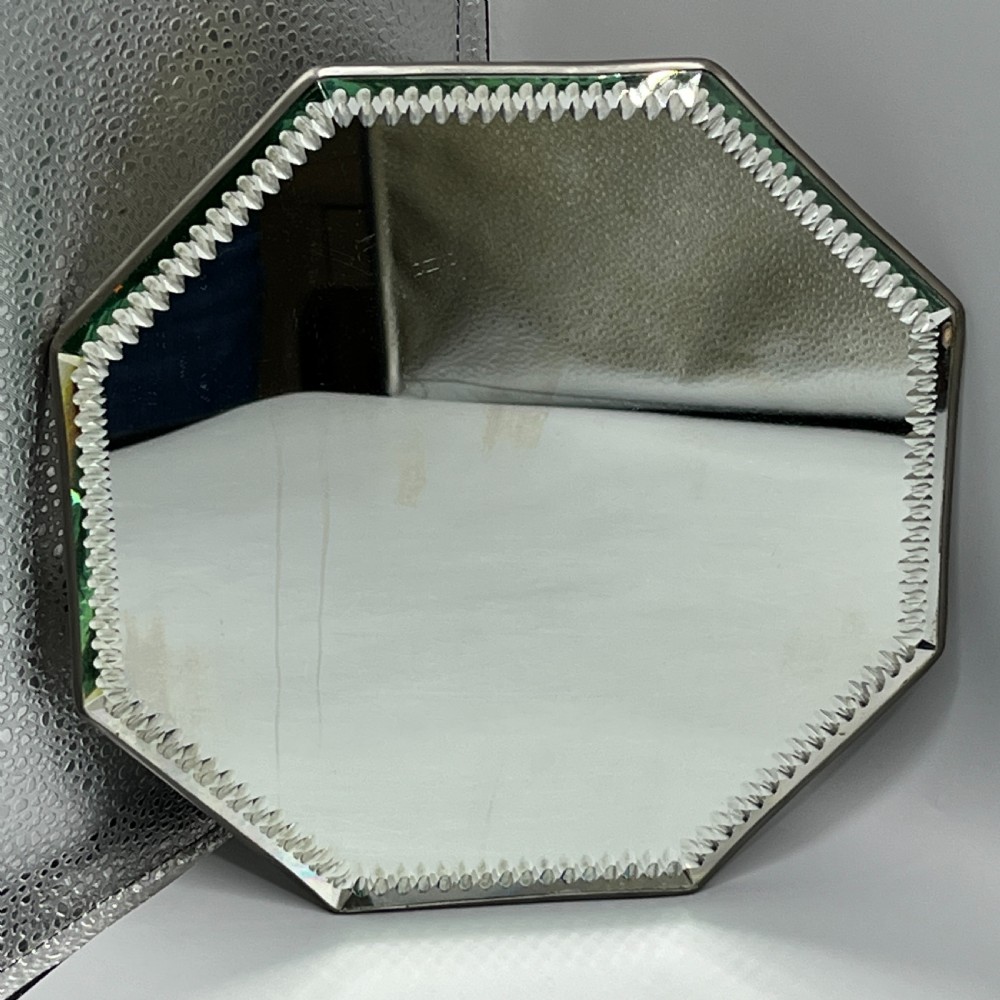 An octagonal frameless mirror featuring a decoratively cut bevelled interior border pattern on a clear mirrored surface.