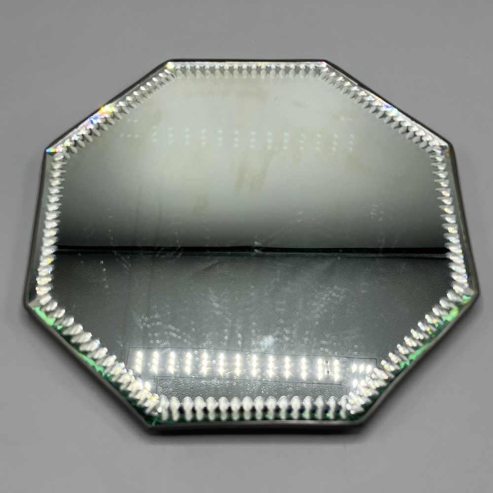 An octagonal frameless mirror featuring a decoratively cut bevelled interior border pattern on a clear mirrored surface. View VII