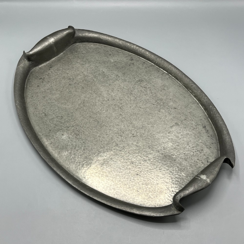 An oval pewter serving tray featuring a hand-hammered surface texture and raised integral handles on opposite ends. View II