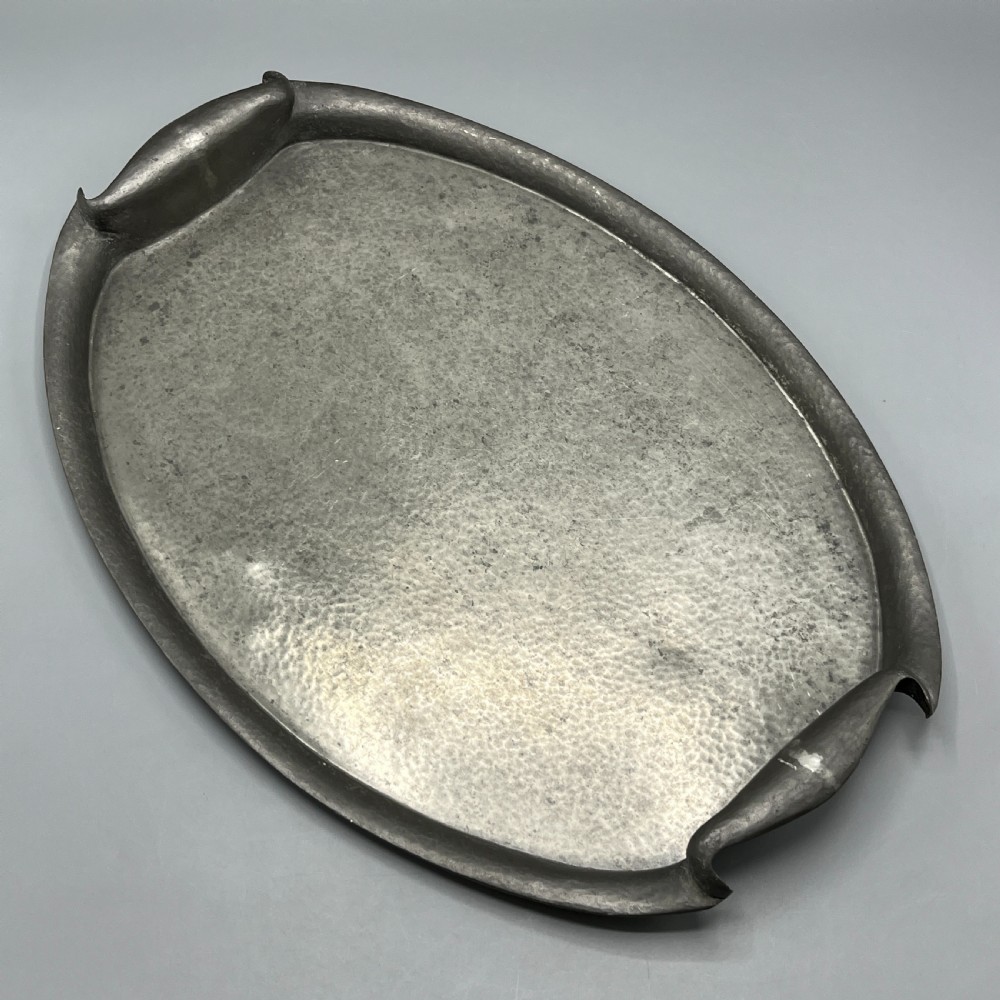 An oval pewter serving tray featuring a hand-hammered surface texture and raised integral handles on opposite ends. View III