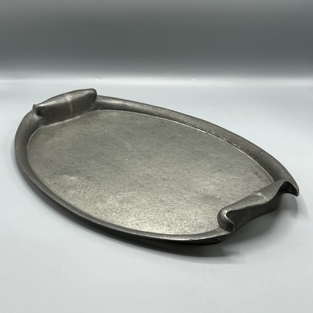 An oval pewter serving tray featuring a hand-hammered surface texture and raised integral handles on opposite ends. View IV
