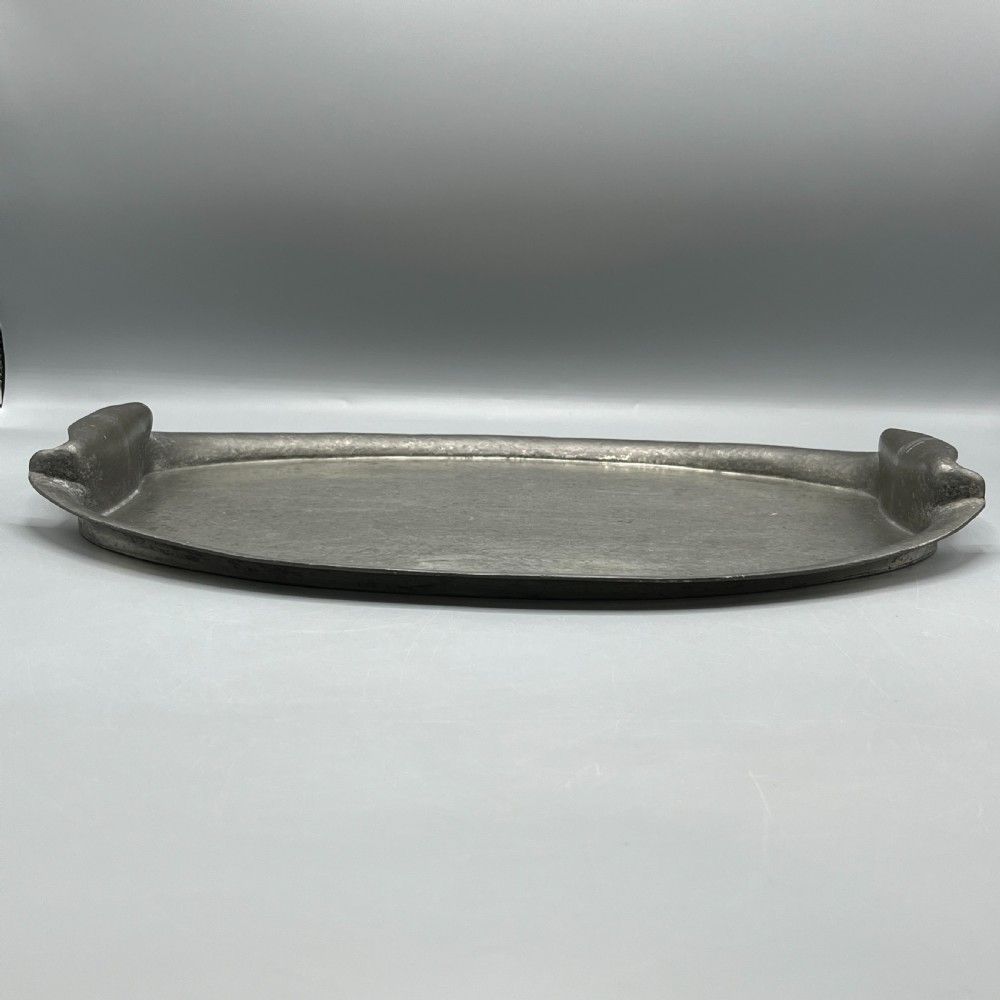 An oval pewter serving tray featuring a hand-hammered surface texture and raised integral handles on opposite ends. View V