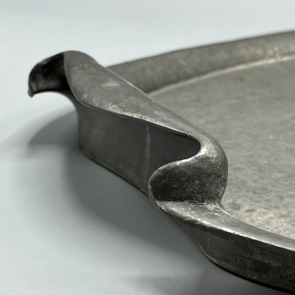 An oval pewter serving tray featuring a hand-hammered surface texture and raised integral handles on opposite ends. View VI