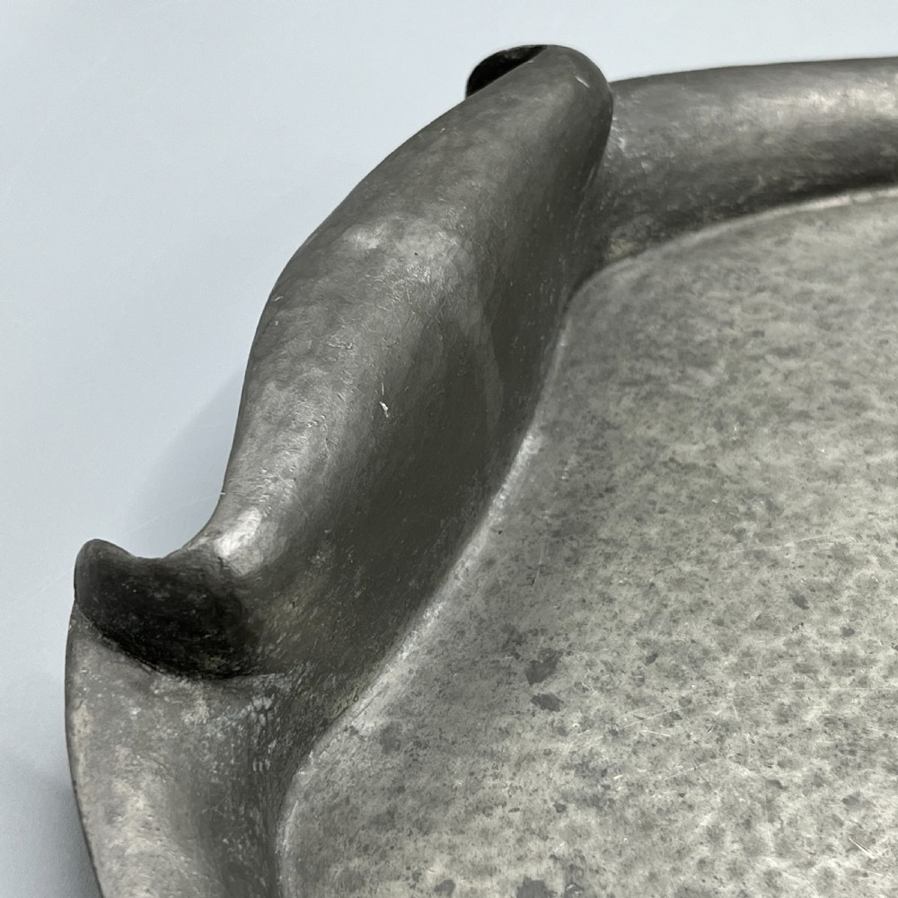 An oval pewter serving tray featuring a hand-hammered surface texture and raised integral handles on opposite ends. View IX