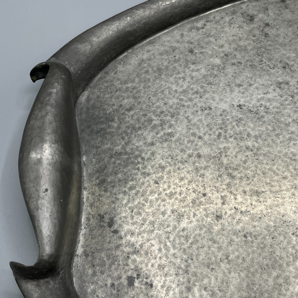 An oval pewter serving tray featuring a hand-hammered surface texture and raised integral handles on opposite ends. View XI
