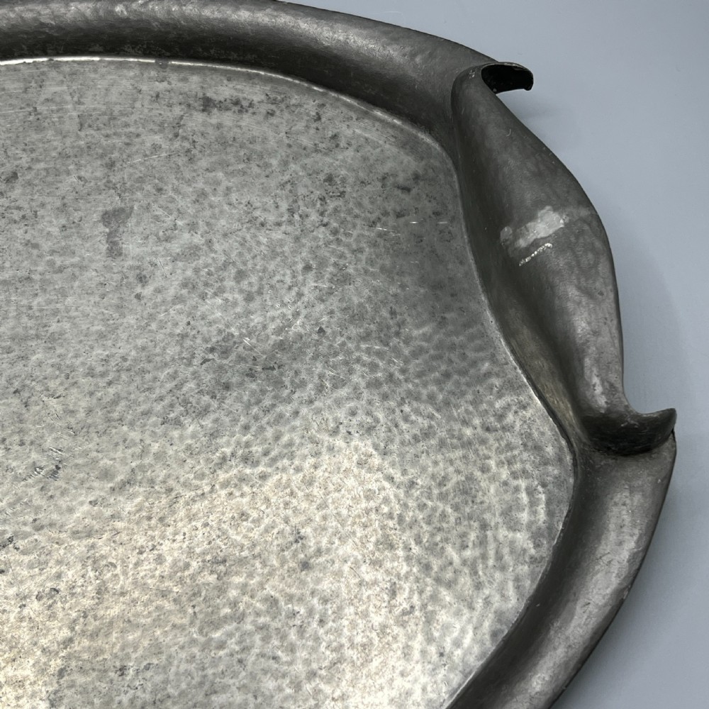 An oval pewter serving tray featuring a hand-hammered surface texture and raised integral handles on opposite ends. View XIV