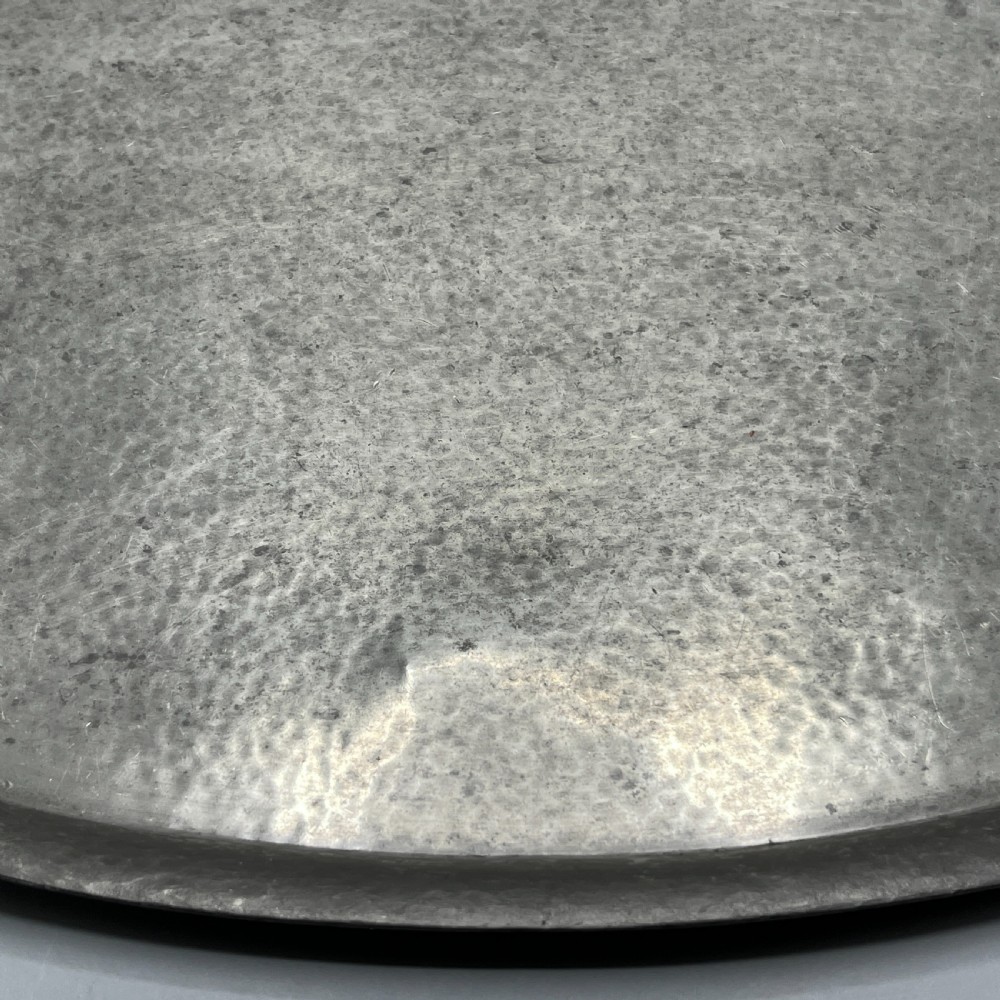 An oval pewter serving tray featuring a hand-hammered surface texture and raised integral handles on opposite ends. View XVI
