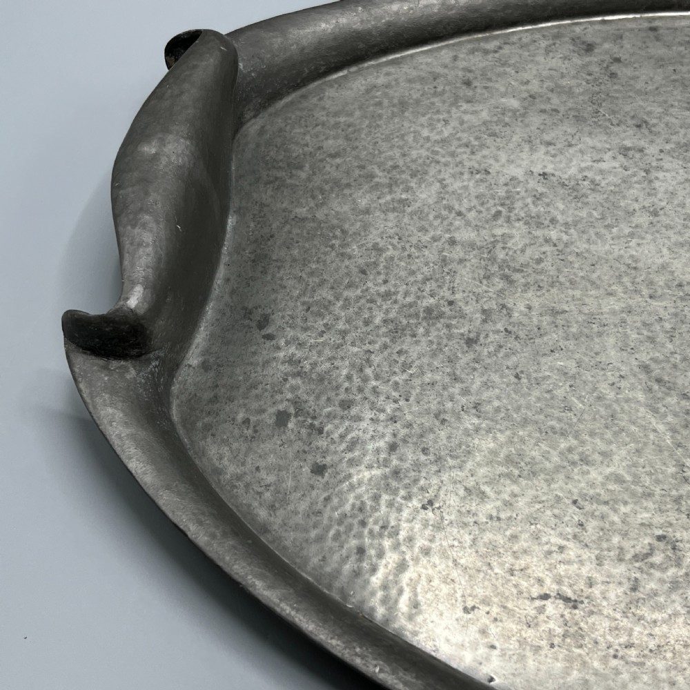 An oval pewter serving tray featuring a hand-hammered surface texture and raised integral handles on opposite ends. View XVIII