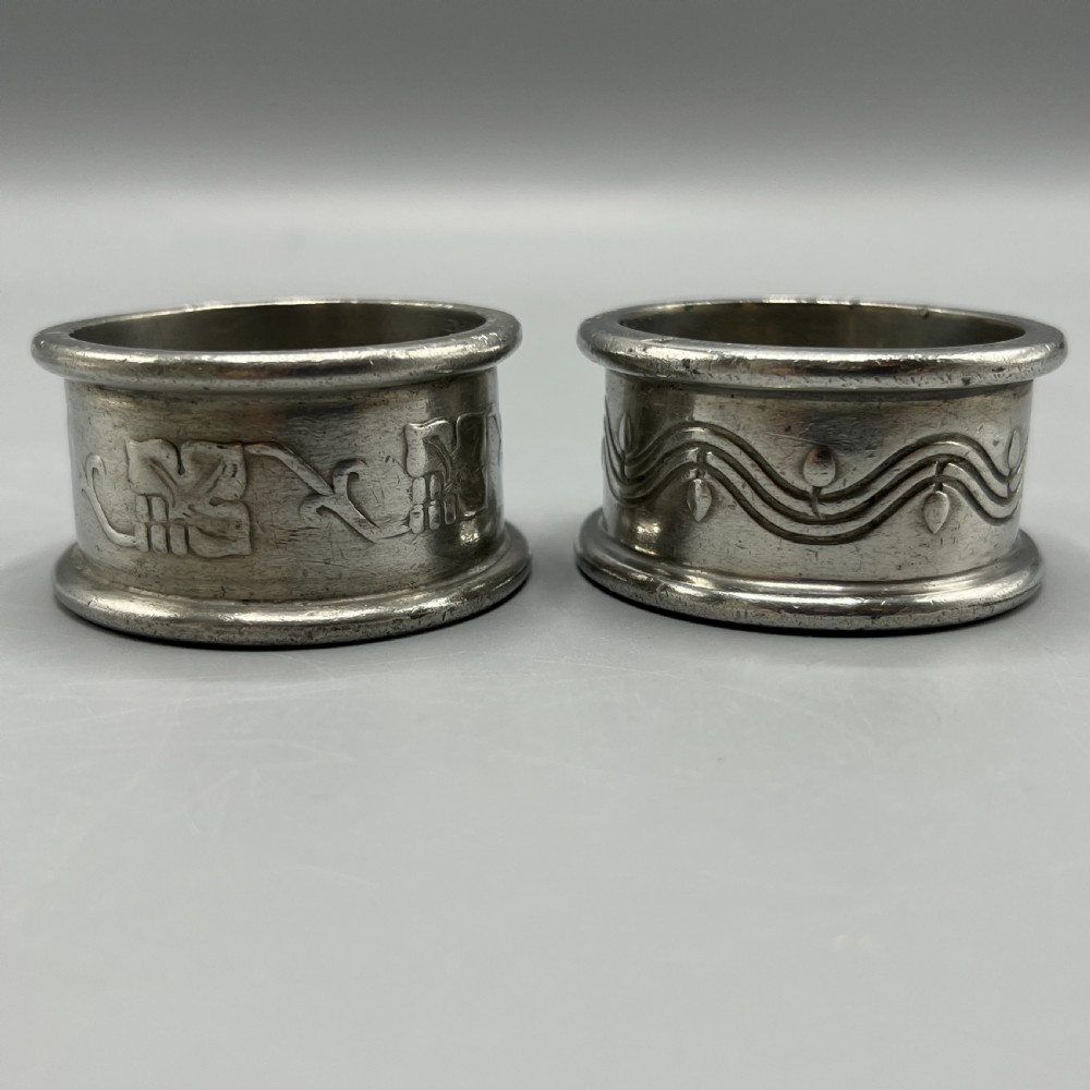 A pair of circular pewter napkin rings decorated with embossed Arts and Crafts stylised floral and tendril motifs. View III