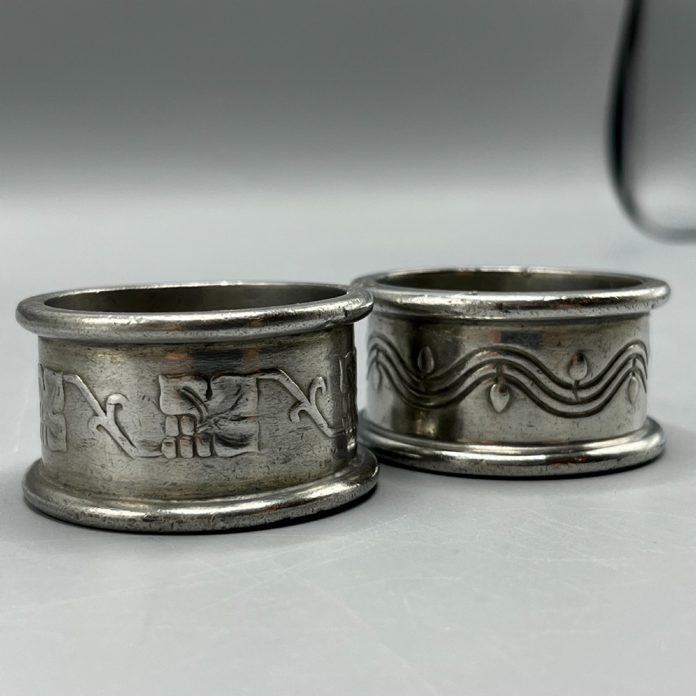 A pair of circular pewter napkin rings decorated with embossed Arts and Crafts stylised floral and tendril motifs. View IV