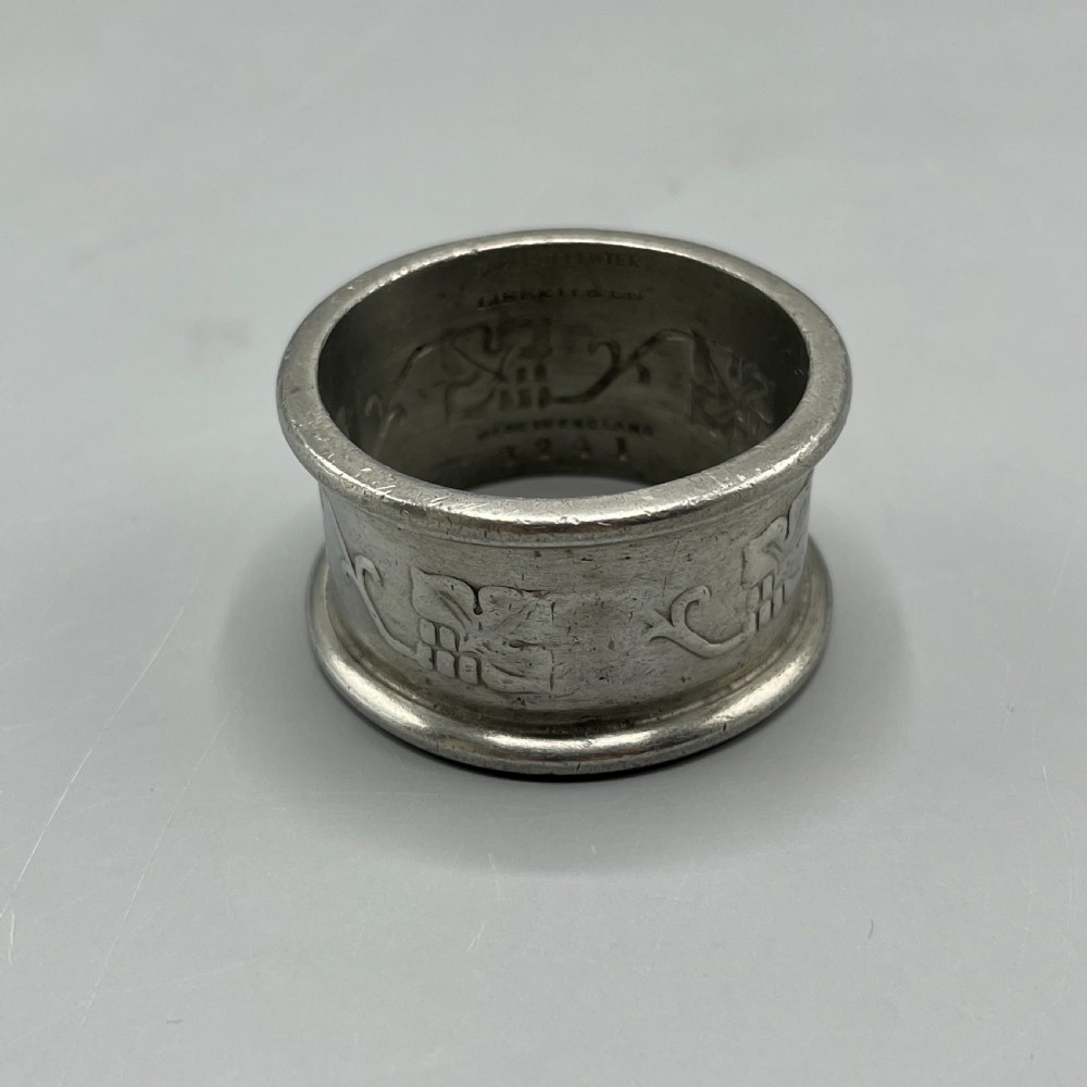 A pair of circular pewter napkin rings decorated with embossed Arts and Crafts stylised floral and tendril motifs. View V