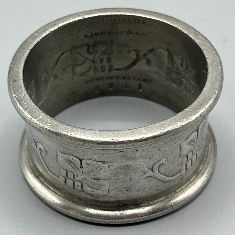 A pair of circular pewter napkin rings decorated with embossed Arts and Crafts stylised floral and tendril motifs. View VI