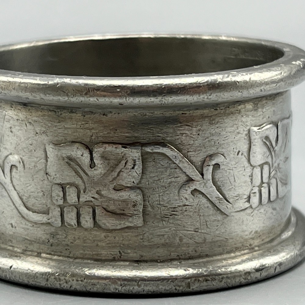 A pair of circular pewter napkin rings decorated with embossed Arts and Crafts stylised floral and tendril motifs. View VII