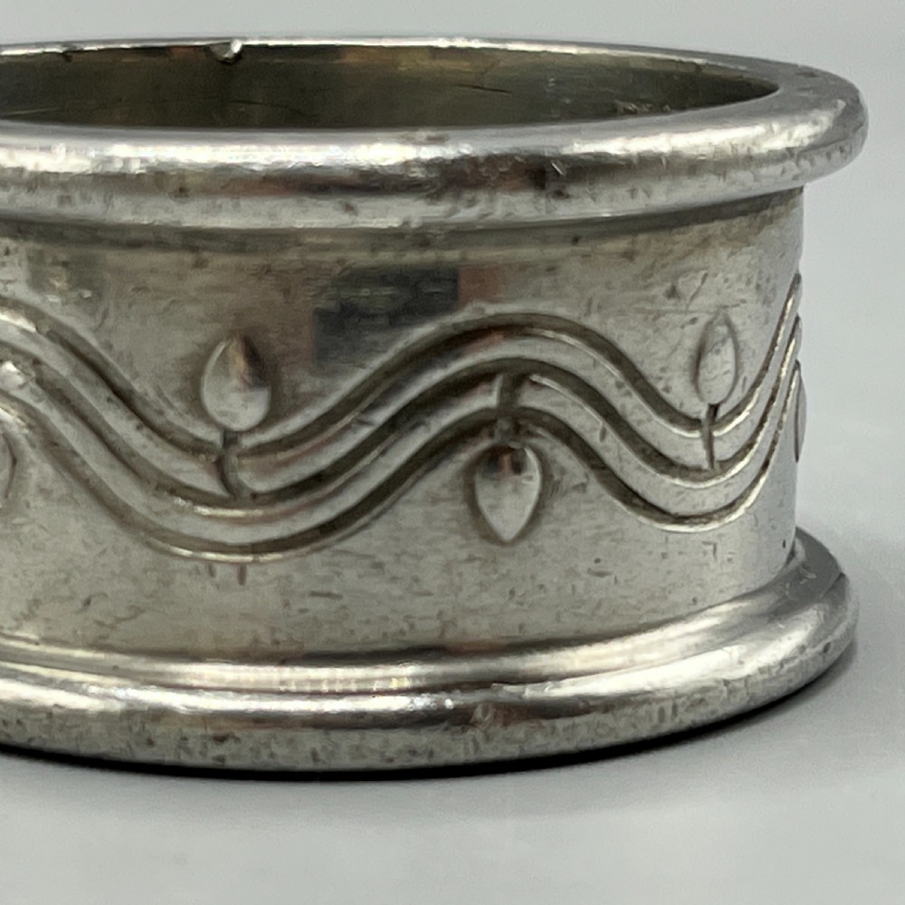A pair of circular pewter napkin rings decorated with embossed Arts and Crafts stylised floral and tendril motifs. View VIII