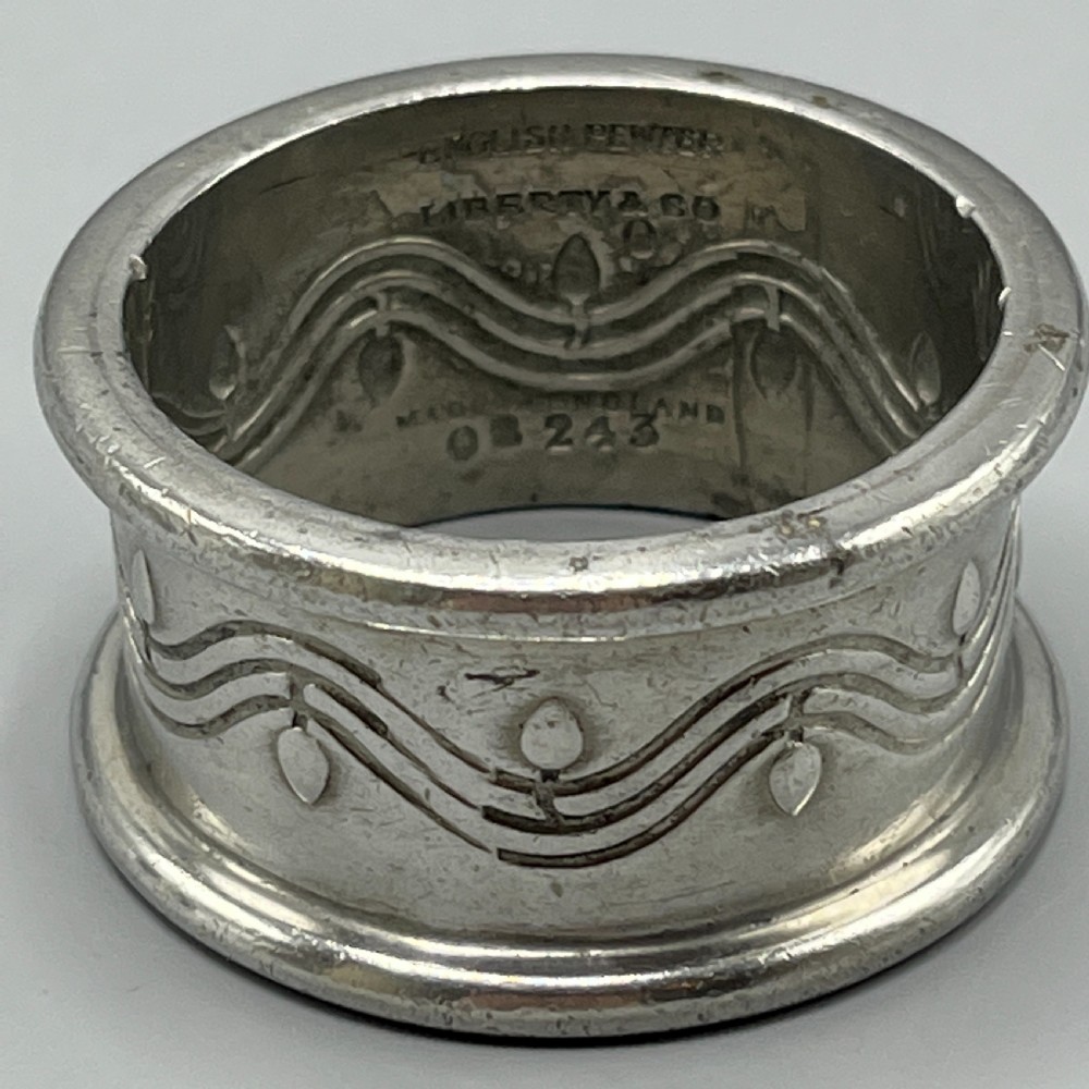 A pair of circular pewter napkin rings decorated with embossed Arts and Crafts stylised floral and tendril motifs. View IX