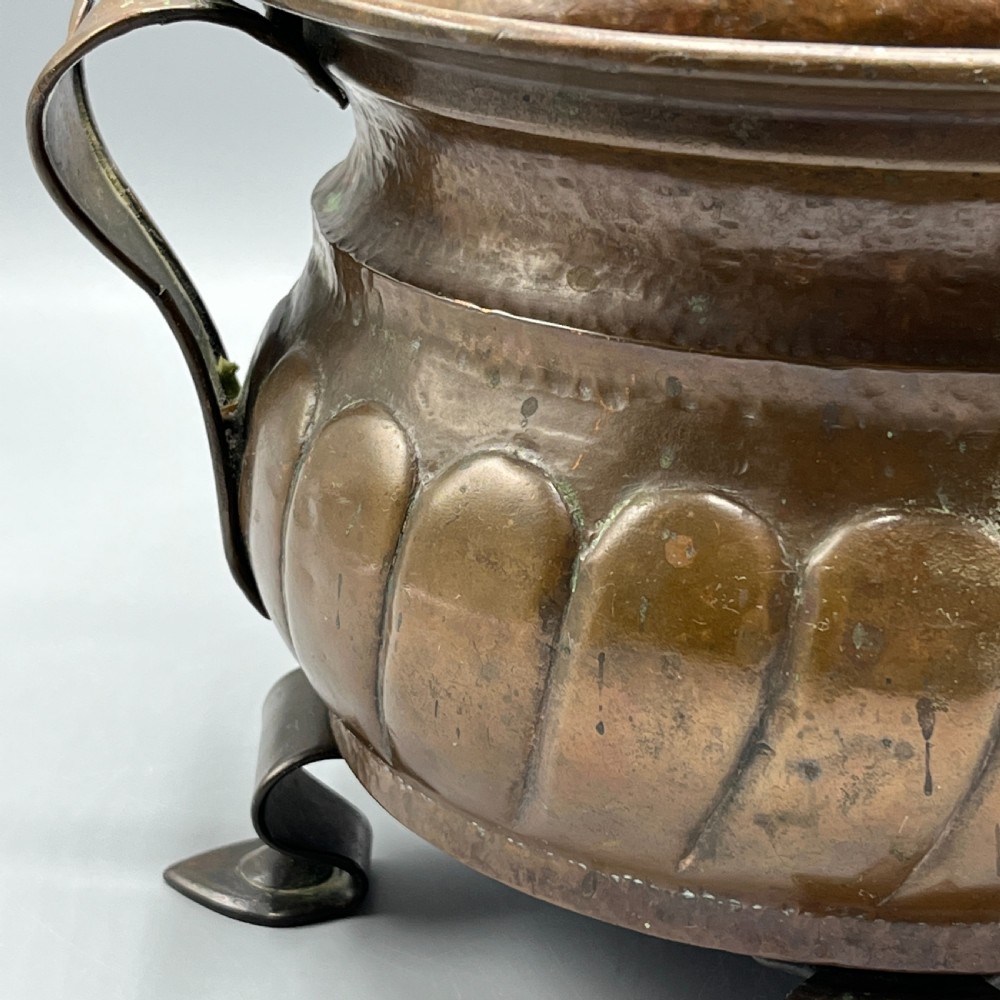 A hand-hammered solid copper Arts and Crafts jardiniere featuring curved side handles, lobed lower body detailing, and four raised feet. View XIII