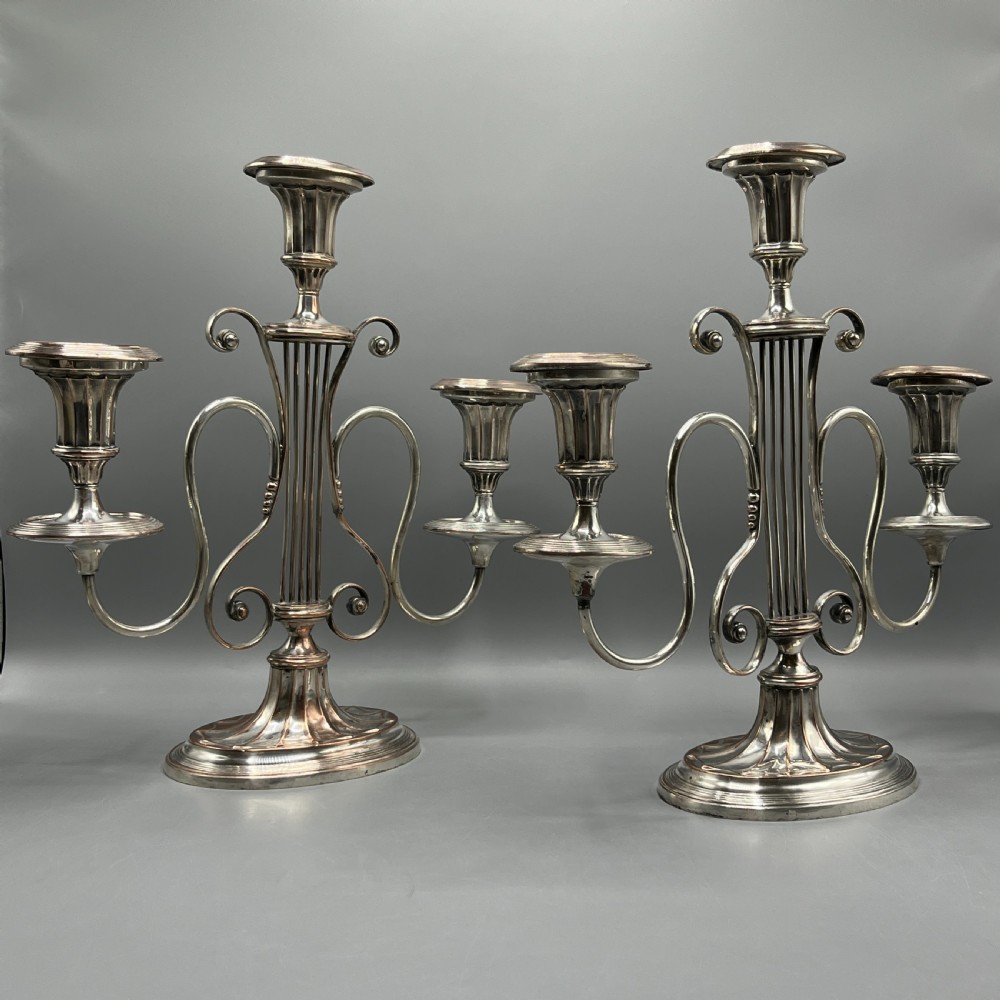 A pair of Georgian silver-plated three-light candelabra with lyre-shaped columns and scrolling branches.