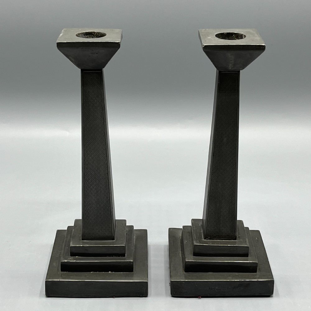A pair of dark grey Art Deco pewter candlesticks featuring stepped square bases and tapered central columns. View III