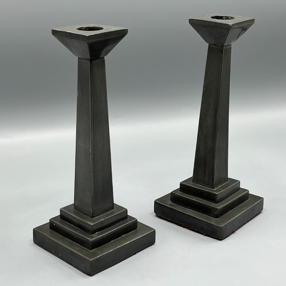 A pair of dark grey Art Deco pewter candlesticks featuring stepped square bases and tapered central columns. View IV