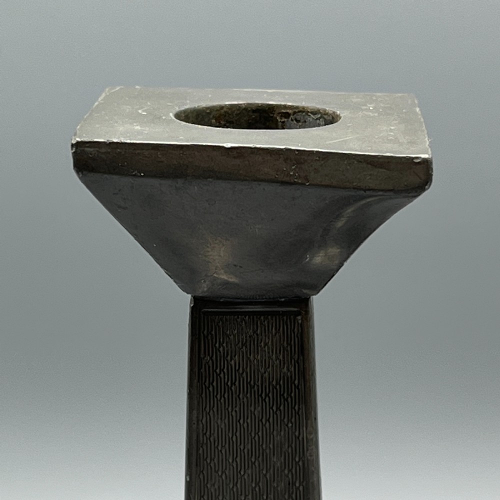 A pair of dark grey Art Deco pewter candlesticks featuring stepped square bases and tapered central columns. View XII
