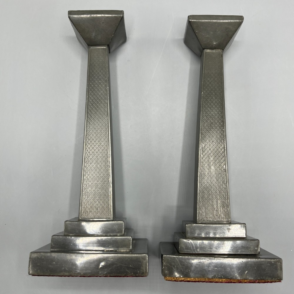 A pair of dark grey Art Deco pewter candlesticks featuring stepped square bases and tapered central columns. View XIV