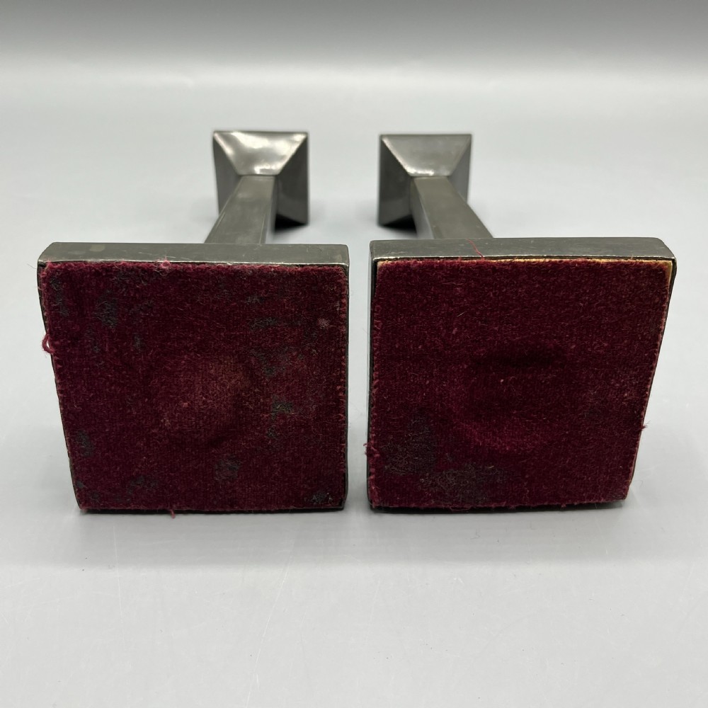 A pair of dark grey Art Deco pewter candlesticks featuring stepped square bases and tapered central columns. View XVI