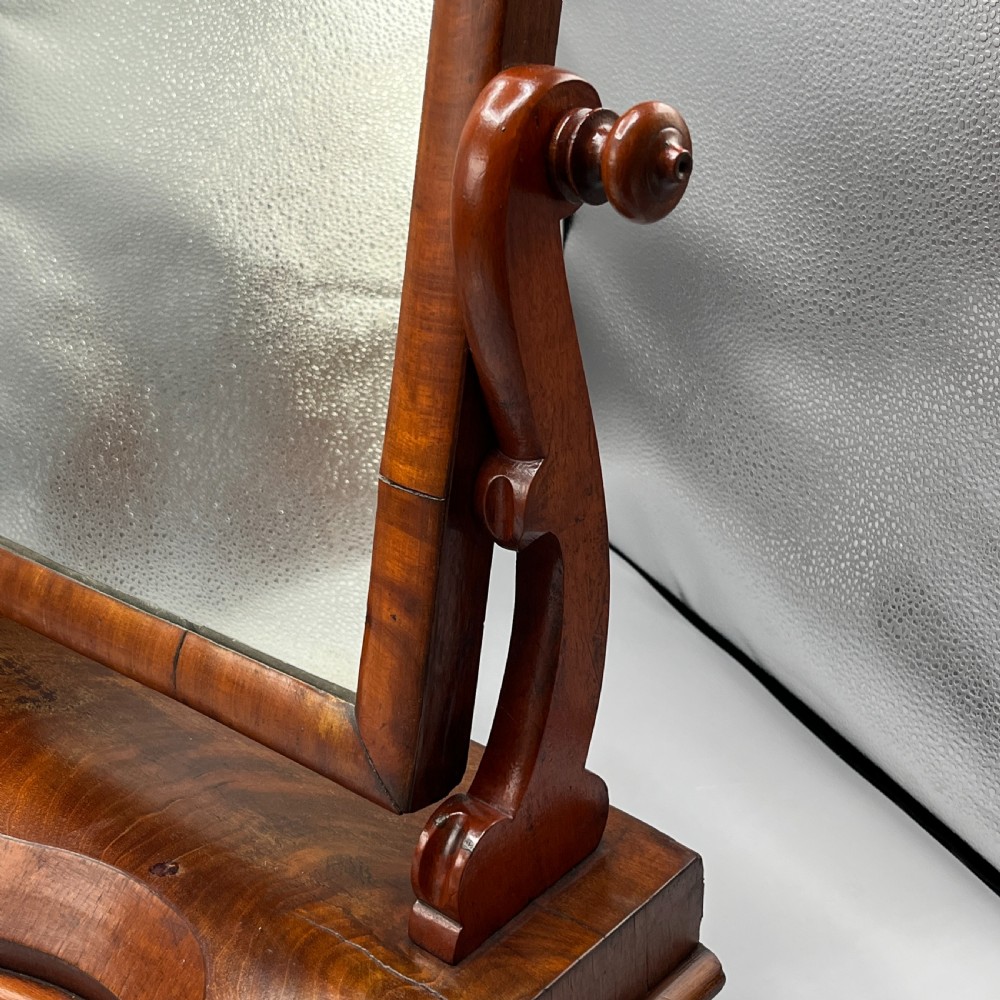 A Victorian mahogany dressing table mirror with an arched swivel frame and carved scroll uprights set on a serpentine base. View V