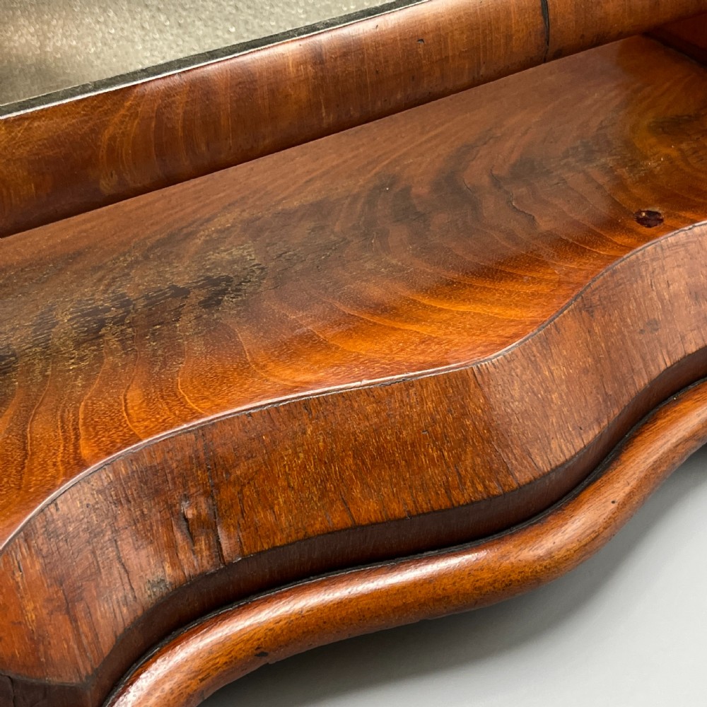 A Victorian mahogany dressing table mirror with an arched swivel frame and carved scroll uprights set on a serpentine base. View XI