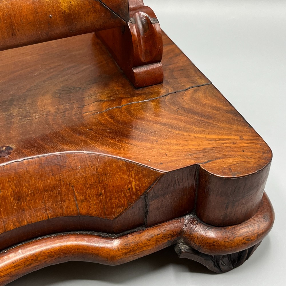A Victorian mahogany dressing table mirror with an arched swivel frame and carved scroll uprights set on a serpentine base. View XII