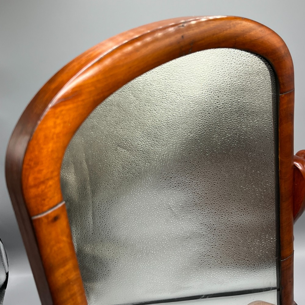 A Victorian mahogany dressing table mirror with an arched swivel frame and carved scroll uprights set on a serpentine base. View XIII