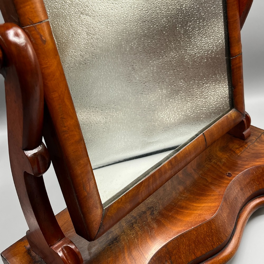 A Victorian mahogany dressing table mirror with an arched swivel frame and carved scroll uprights set on a serpentine base. View XIV