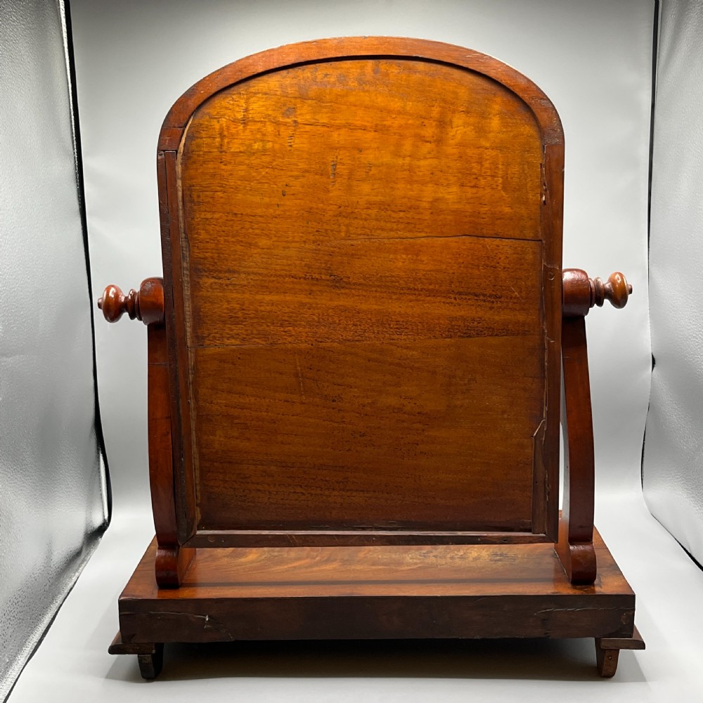 A Victorian mahogany dressing table mirror with an arched swivel frame and carved scroll uprights set on a serpentine base. View XVII