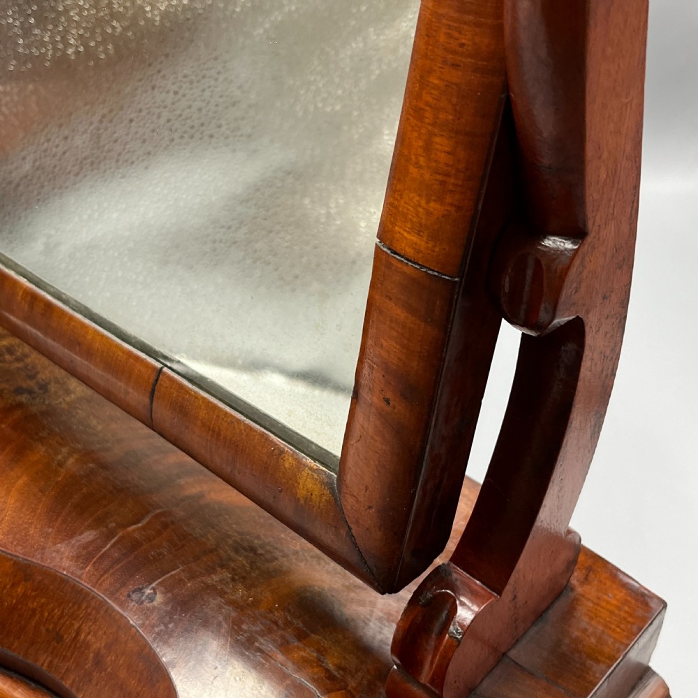 A Victorian mahogany dressing table mirror with an arched swivel frame and carved scroll uprights set on a serpentine base. View XVIII
