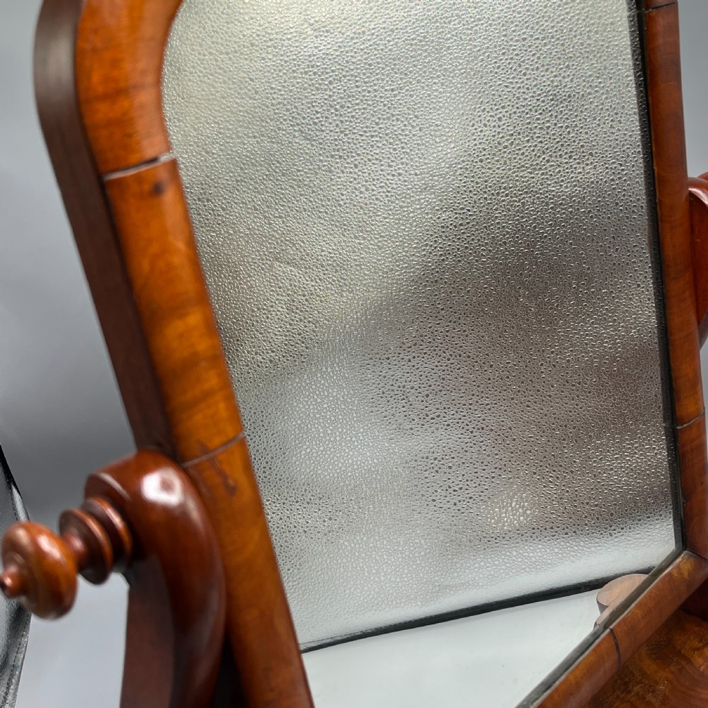A Victorian mahogany dressing table mirror with an arched swivel frame and carved scroll uprights set on a serpentine base. View XIX