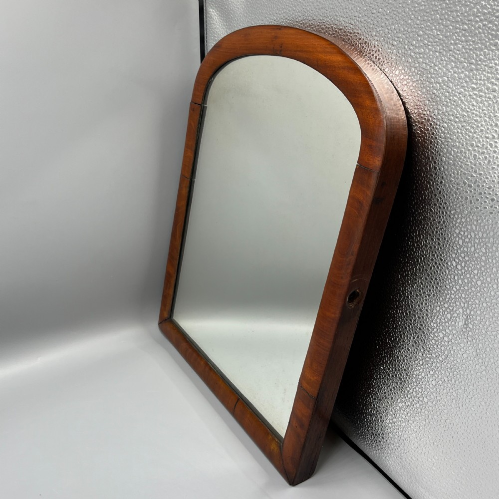A Victorian mahogany dressing table mirror with an arched swivel frame and carved scroll uprights set on a serpentine base. View XXIV