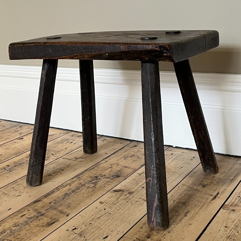 A rustic dark oak four-legged stool featuring a thick rectangular top with four visible circular wedged tenons and splayed faceted legs. View XIII