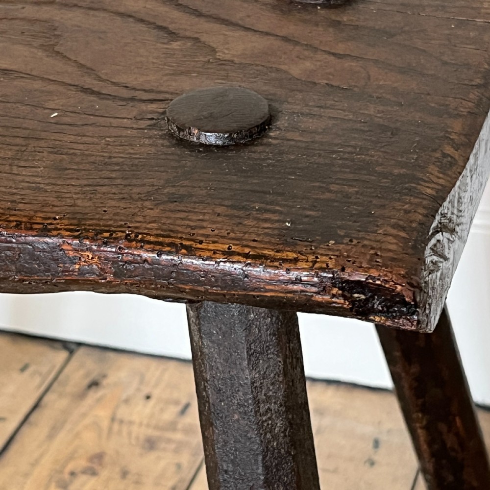 A rustic dark oak four-legged stool featuring a thick rectangular top with four visible circular wedged tenons and splayed faceted legs. View XIV