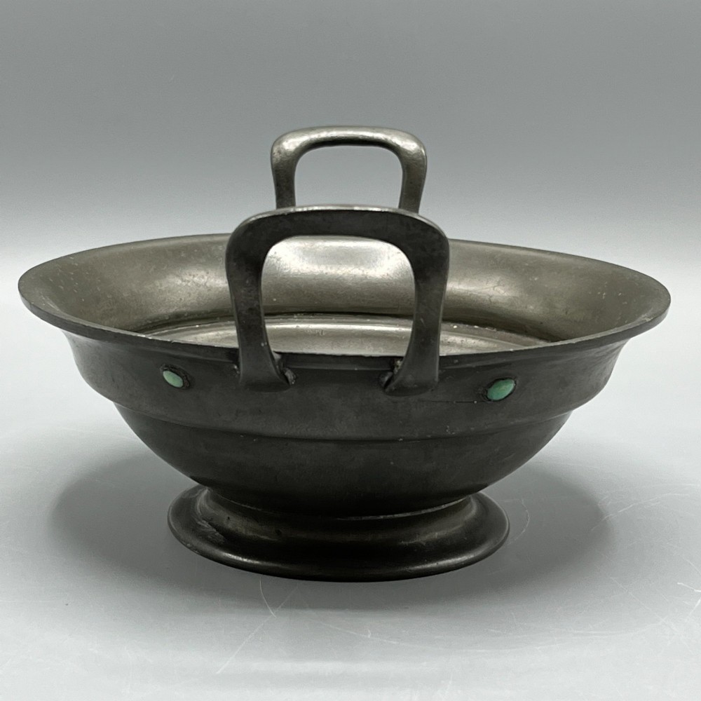 An Arts and Crafts pewter porringer bowl featuring twin raised handles, a pedestal base, and small turquoise cabochons set into the exterior rim. View V